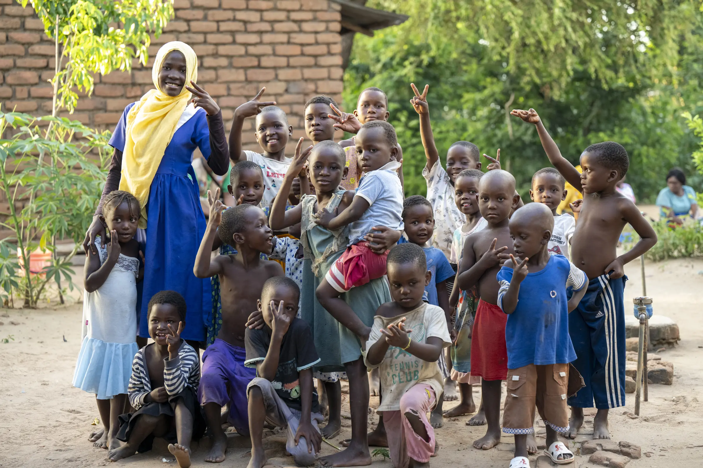 A woman and a large group of children gather for a portrait in a Malawi village