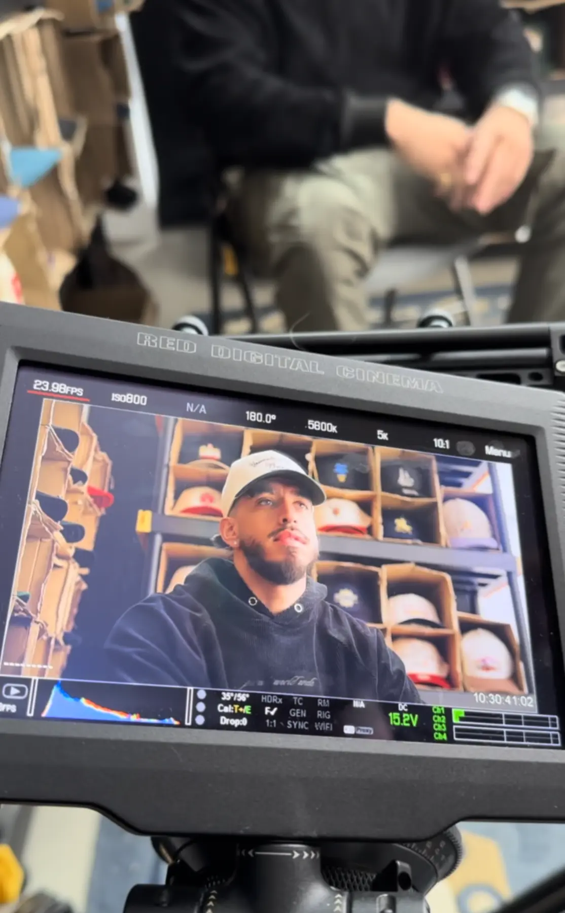 A production monitor shows a Pirate Worldwide founder framed by shelves of the label's hats