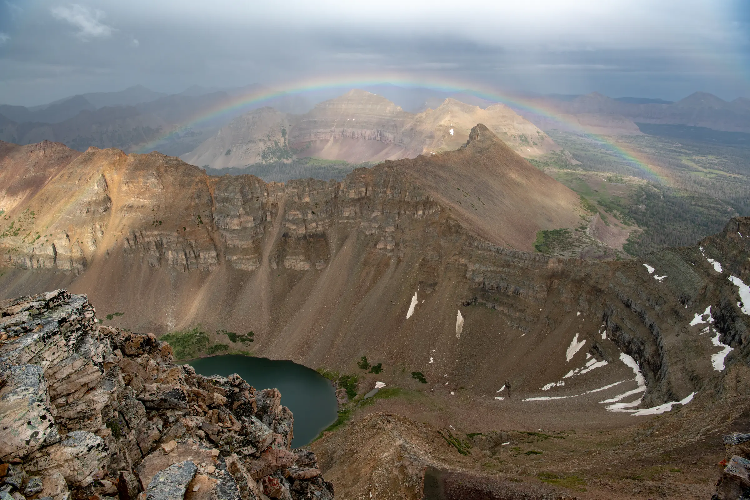A rainbow spanning the rugged mountains and alpine basin below