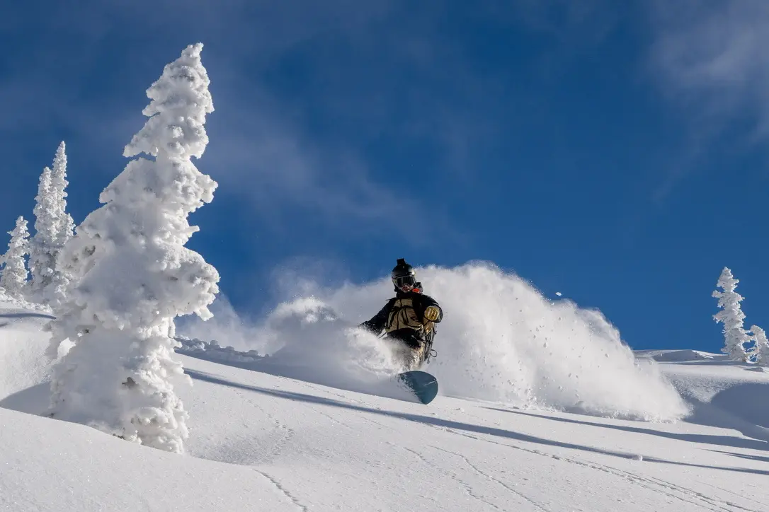 Brian Berec snowboarding through deep powder in Grizzly Gulch