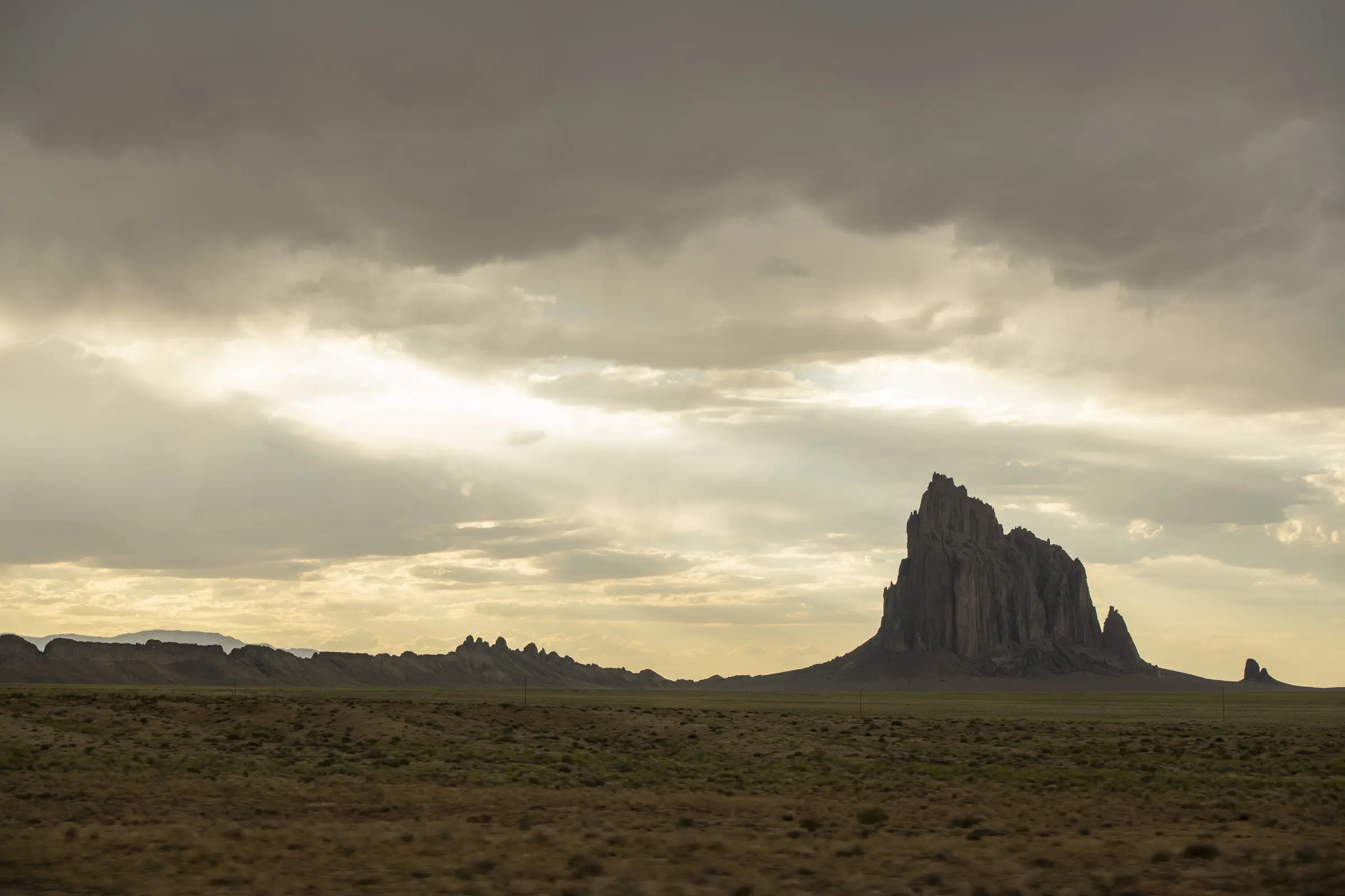 Shiprock rising beneath a break in a stormy sky