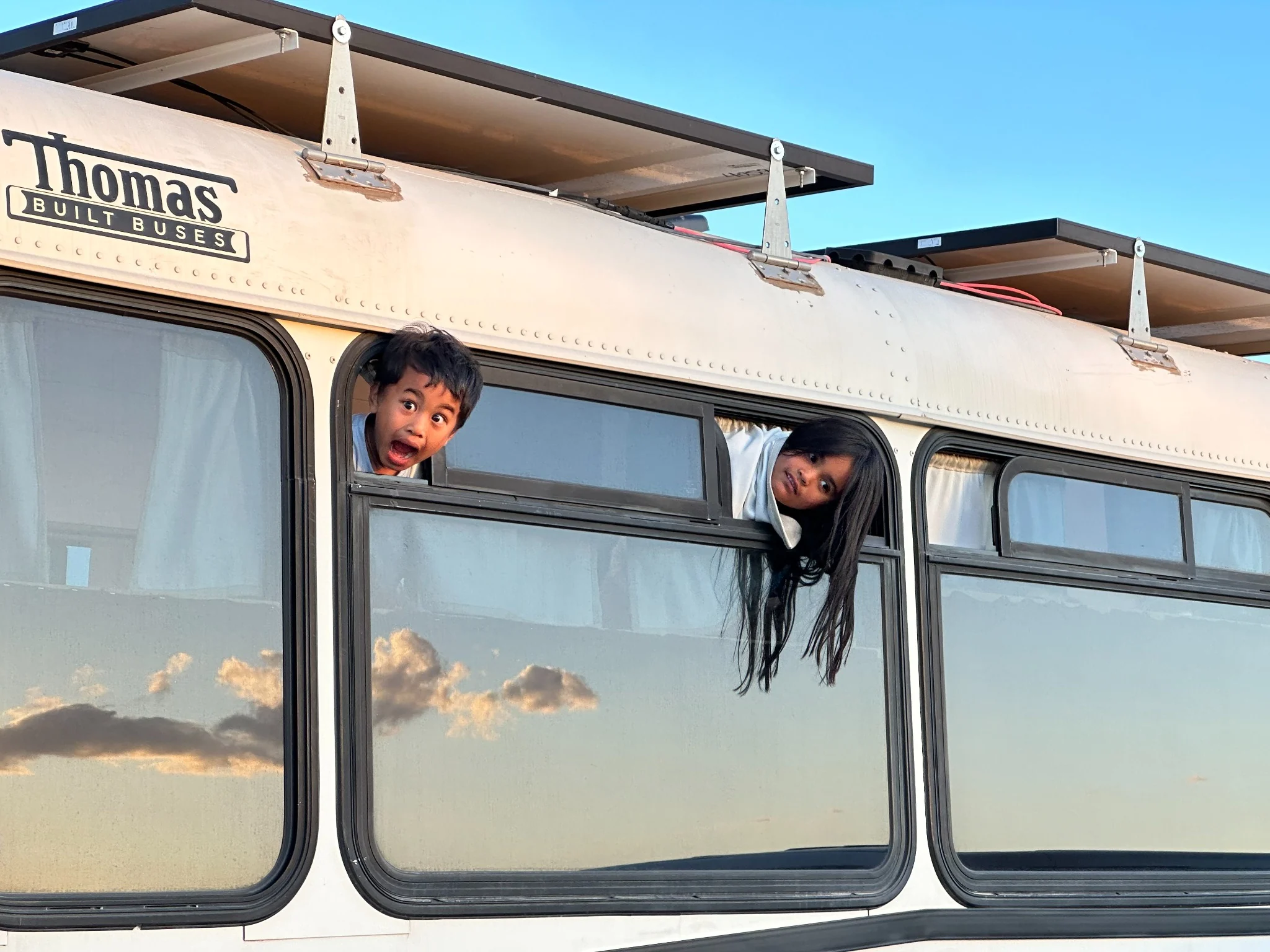 Two children leaning out of Sunny’s bus windows